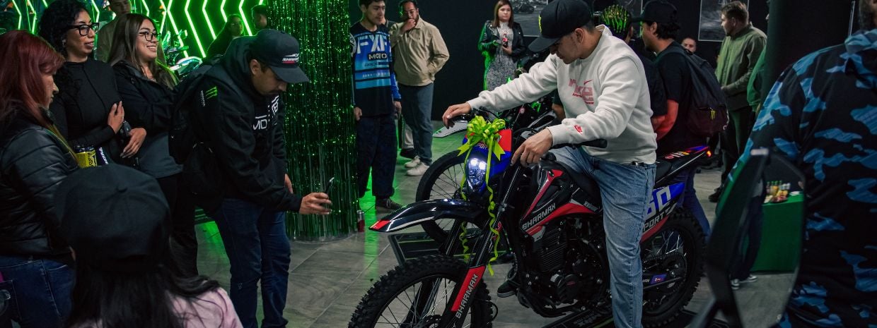 Cliente probando una motocicleta Sharmax 250 Sport en el showroom durante el evento de la agencia