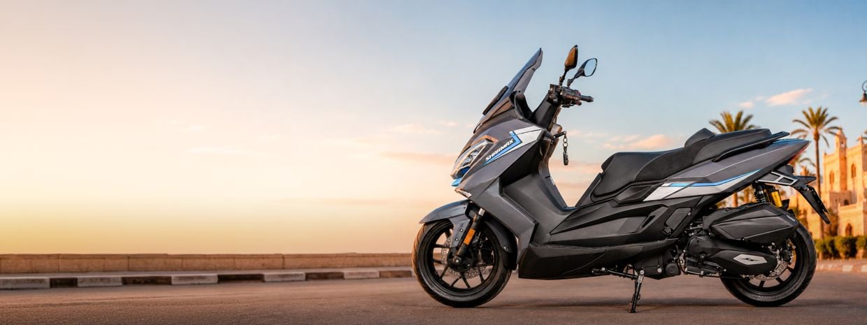 FX 441 EU scooter parked on a waterfront at sunset with a city skyline in the background